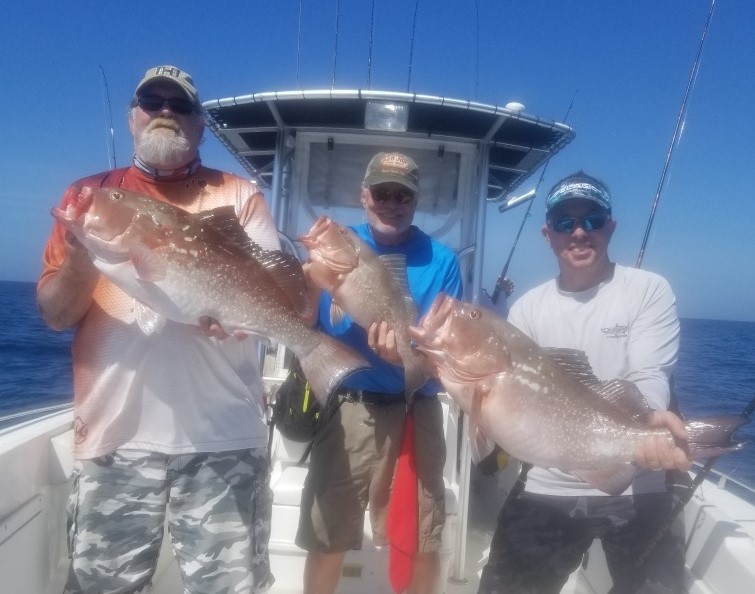 Two men holding a Grouper caught on their deep sea fishing charter off the shore of St. Petersburg, FL.